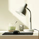 A modern workspace featuring an energy-efficient LED lamp, a laptop, and a refreshing drink on a desk.